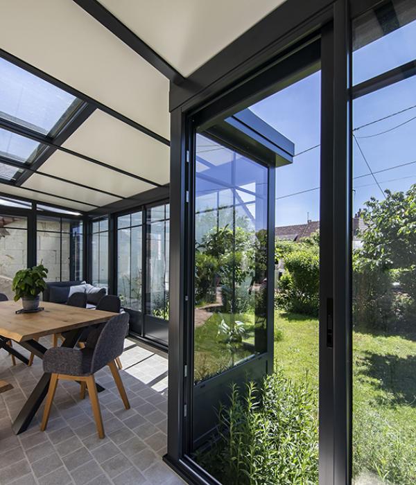 Vue d'un jardin depuis la v&eacute;randa aluminium d'une maison